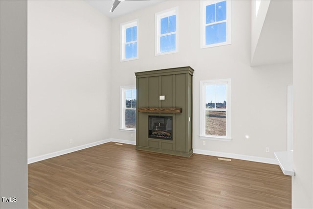 unfurnished living room featuring a high ceiling, ceiling fan, and dark wood-type flooring