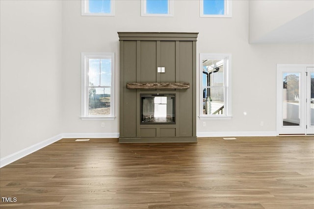 unfurnished living room featuring a towering ceiling and wood-type flooring