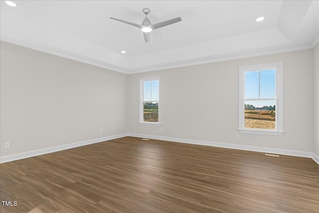 unfurnished room featuring dark hardwood / wood-style floors, a raised ceiling, ceiling fan, and ornamental molding