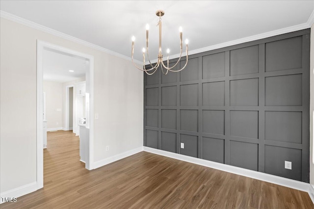 unfurnished dining area featuring hardwood / wood-style floors, ornamental molding, and a notable chandelier