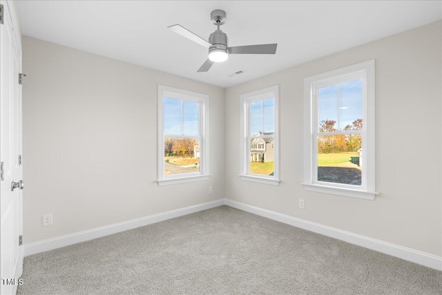 carpeted empty room with a wealth of natural light and ceiling fan