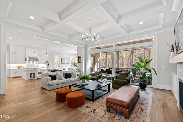 living room with coffered ceiling, plenty of natural light, light hardwood / wood-style floors, and beamed ceiling