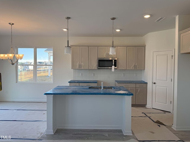 kitchen with gray cabinets, stainless steel microwave, a sink, and decorative light fixtures