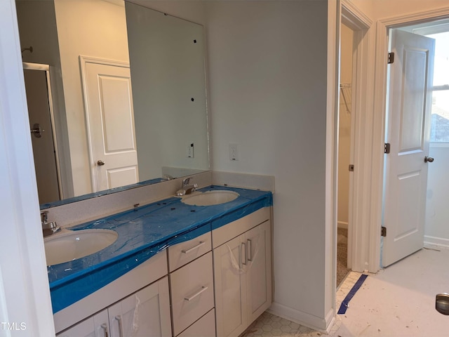 full bath featuring a walk in closet, a sink, baseboards, and double vanity