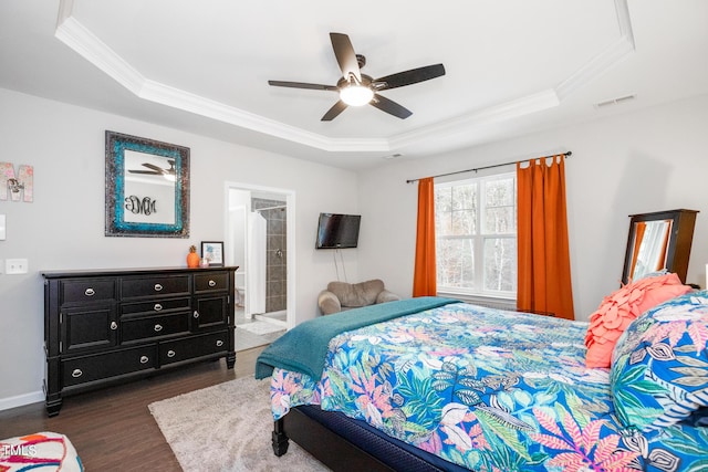 bedroom with a tray ceiling, ensuite bath, ceiling fan, and dark hardwood / wood-style floors