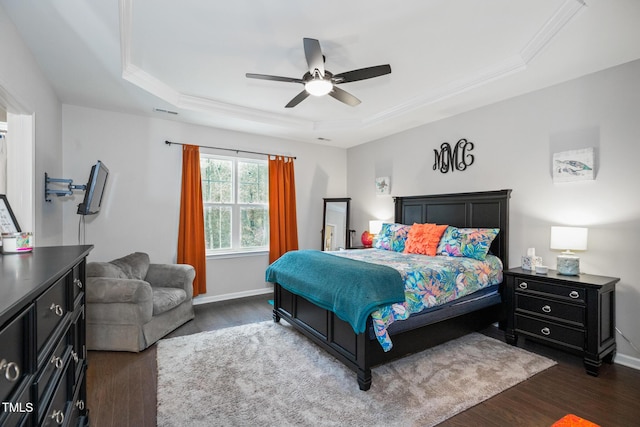 bedroom with a tray ceiling, ceiling fan, and dark wood-type flooring