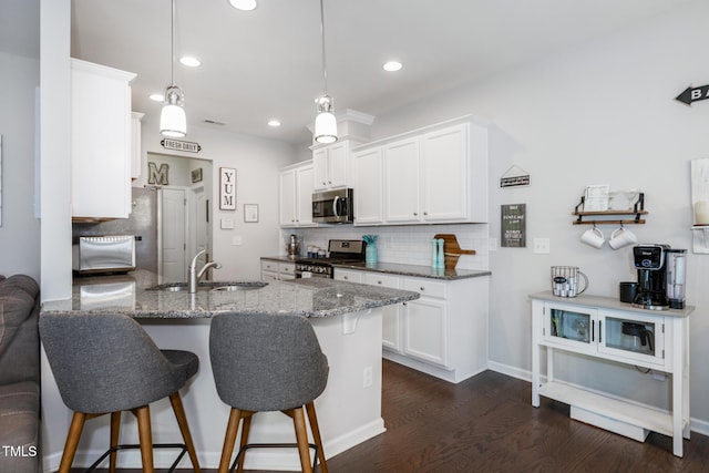 kitchen with sink, hanging light fixtures, dark hardwood / wood-style floors, white cabinetry, and stainless steel appliances