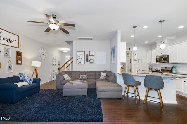 living room featuring dark hardwood / wood-style floors, ceiling fan, and sink