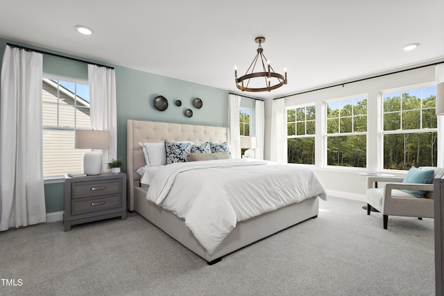 bedroom featuring light carpet, a chandelier, and multiple windows