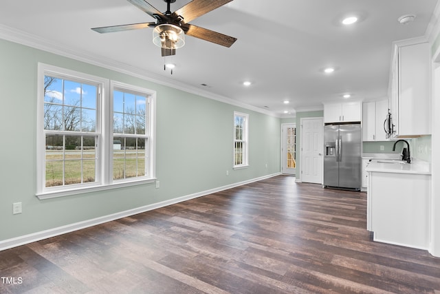 unfurnished living room with ceiling fan, dark wood-type flooring, and a healthy amount of sunlight