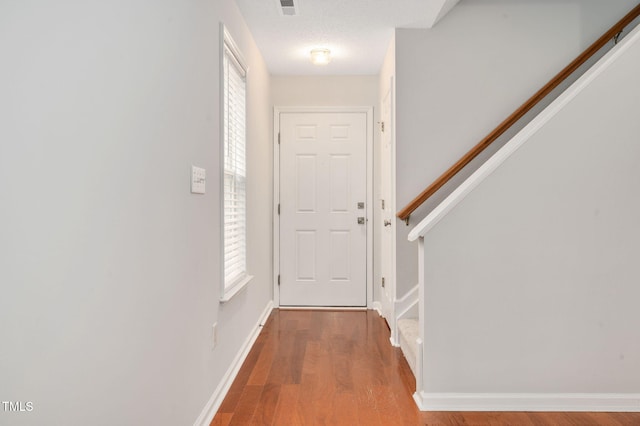 doorway with a textured ceiling, light hardwood / wood-style floors, and a healthy amount of sunlight