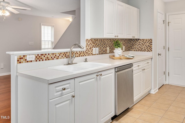 kitchen featuring white cabinets, sink, stainless steel dishwasher, light tile patterned floors, and tasteful backsplash