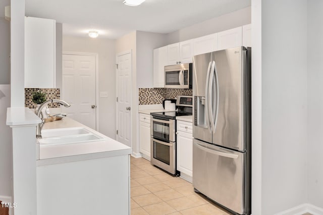 kitchen with appliances with stainless steel finishes, tasteful backsplash, sink, white cabinetry, and light tile patterned flooring