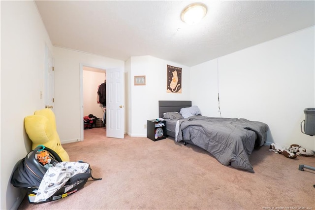 bedroom with a spacious closet, light carpet, and a closet