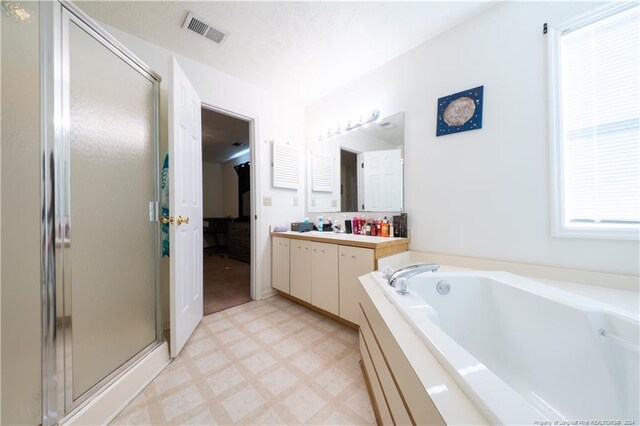 bathroom featuring plus walk in shower, a textured ceiling, and vanity