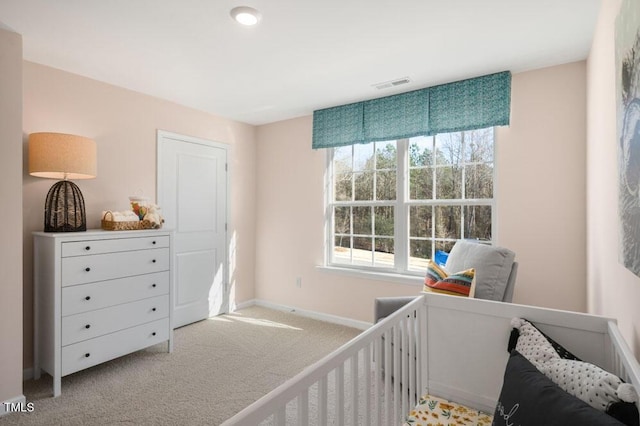 bedroom with light carpet and a nursery area