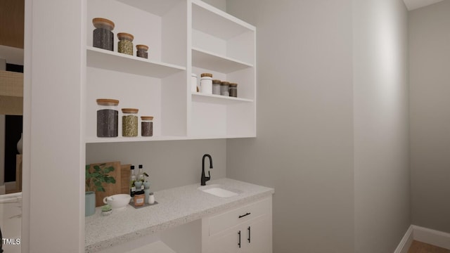 bar featuring light stone countertops and sink