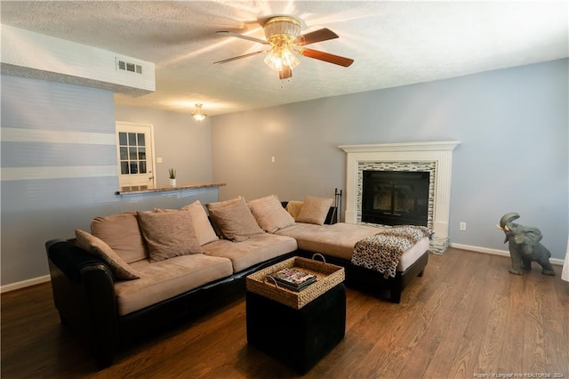 living room featuring ceiling fan, a fireplace, dark wood-type flooring, and a textured ceiling