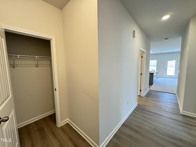 corridor featuring dark wood-type flooring and baseboards