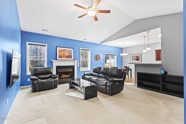 carpeted living room with ceiling fan with notable chandelier, lofted ceiling, and a wealth of natural light