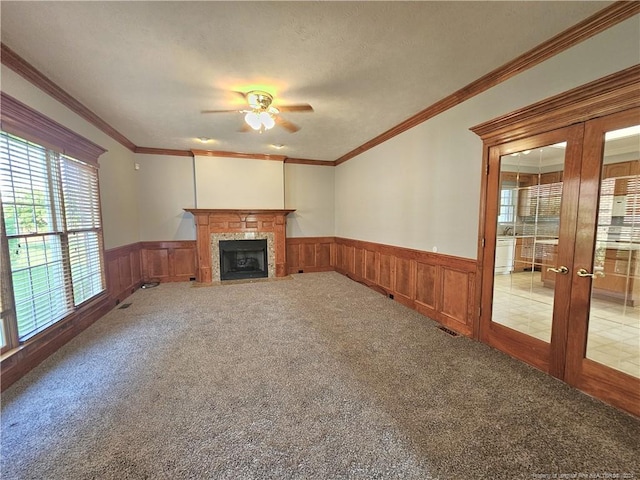 unfurnished living room featuring carpet, ceiling fan, and crown molding