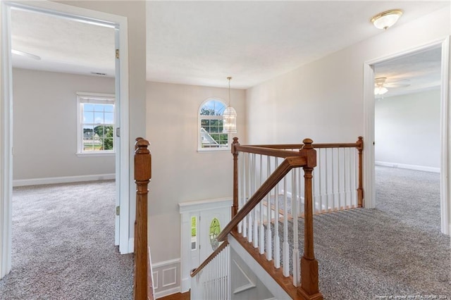 staircase featuring a chandelier, carpet, and a healthy amount of sunlight