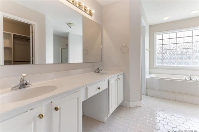 bathroom featuring tile patterned floors, vanity, and tiled bath