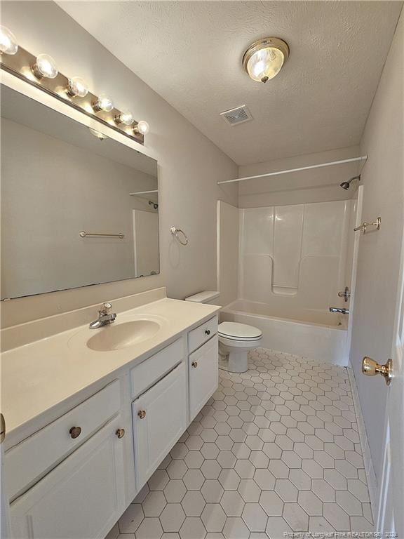 full bathroom featuring vanity,  shower combination, tile patterned floors, toilet, and a textured ceiling