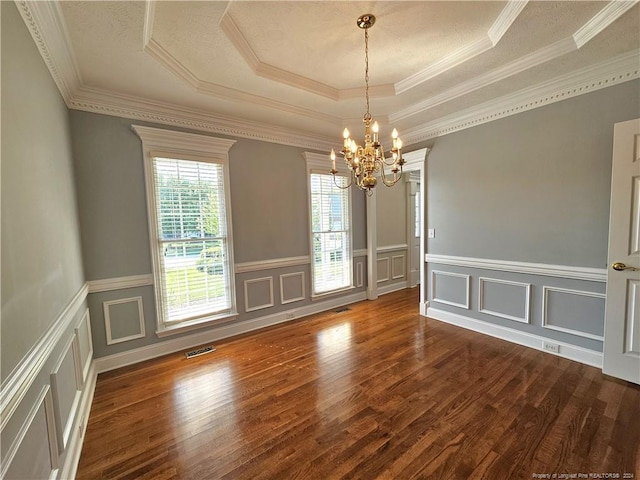 unfurnished dining area featuring a tray ceiling, crown molding, dark wood-type flooring, and a notable chandelier