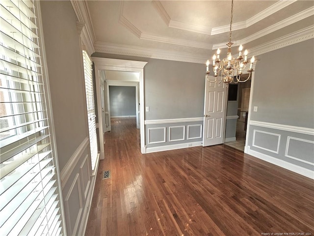 unfurnished dining area featuring a chandelier, ornamental molding, a tray ceiling, and dark wood-type flooring