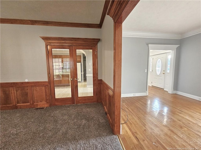 interior space featuring french doors, light wood-type flooring, ornamental molding, and wood walls