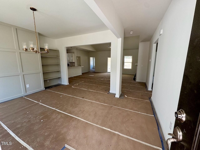 unfurnished living room featuring a chandelier