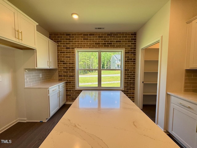 19 Covey Rise Way, Lillington, NC 27546 - kitchen featuring light stone countertops, backsplash, white cabinets, dark wood finished floors, and brick wall