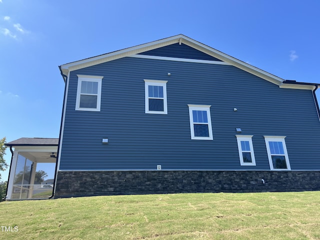 view of side of property featuring a lawn and ceiling fan