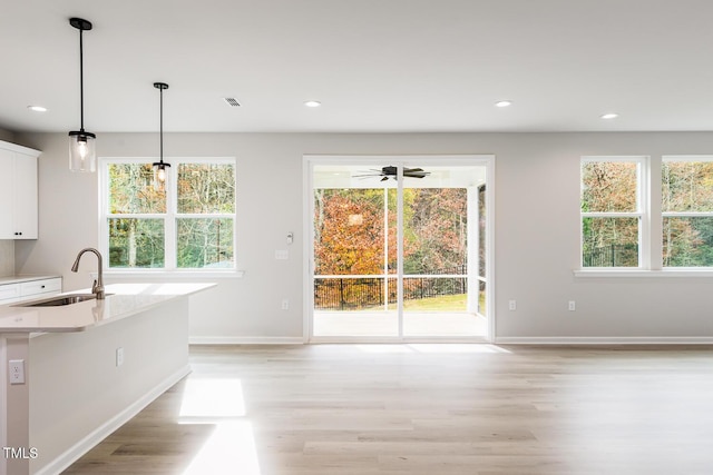 kitchen featuring plenty of natural light, white cabinets, pendant lighting, and sink