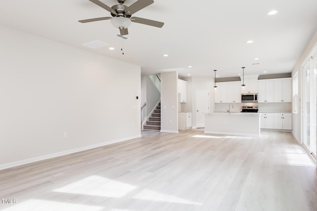 unfurnished living room featuring light wood-type flooring, ceiling fan, and sink