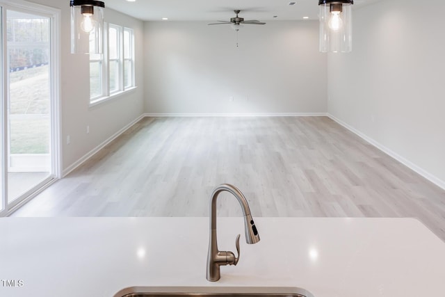 interior space with ceiling fan, sink, and light wood-type flooring