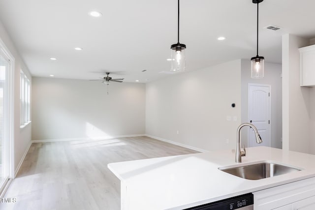 kitchen with white cabinetry, sink, hanging light fixtures, and light wood-type flooring