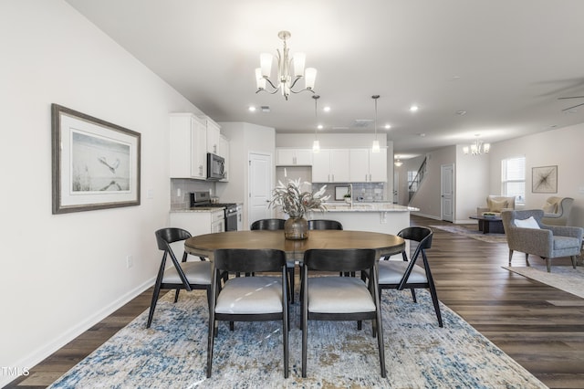 dining room featuring ceiling fan with notable chandelier and dark hardwood / wood-style floors