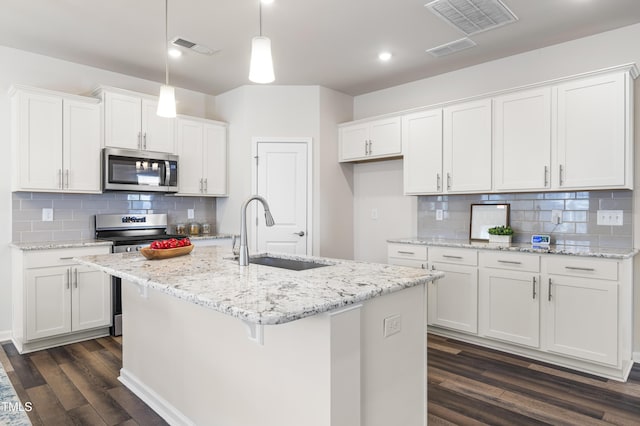 kitchen featuring decorative light fixtures, a center island with sink, sink, stainless steel appliances, and white cabinets