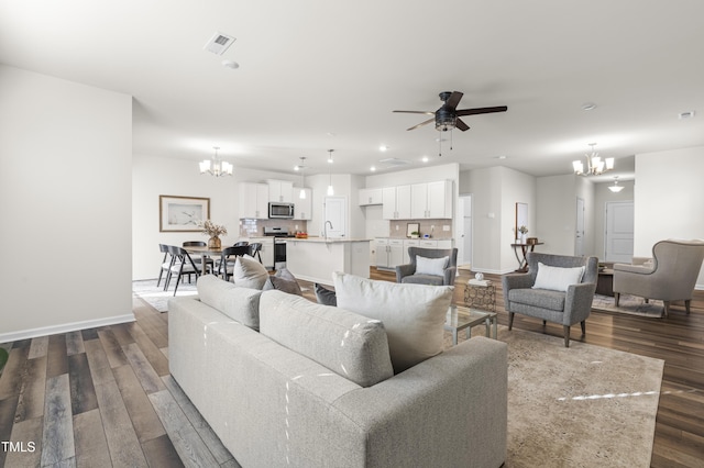 living room featuring ceiling fan with notable chandelier, sink, and dark hardwood / wood-style flooring