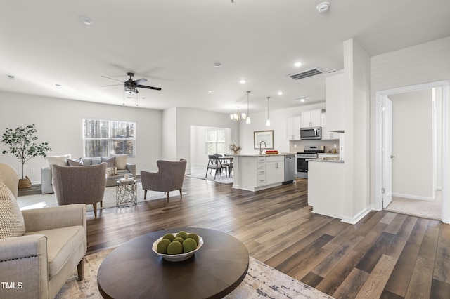 living room featuring ceiling fan with notable chandelier, sink, and dark hardwood / wood-style floors