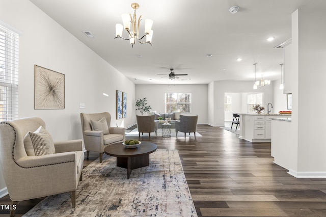 living room with ceiling fan with notable chandelier, sink, and dark hardwood / wood-style flooring