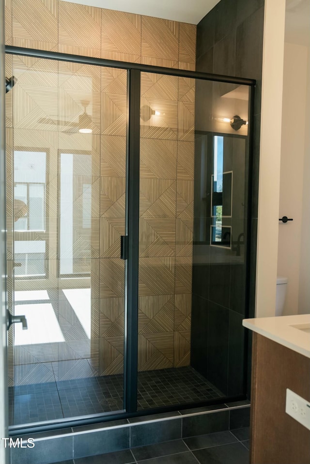 bathroom featuring tile patterned flooring, vanity, toilet, and walk in shower