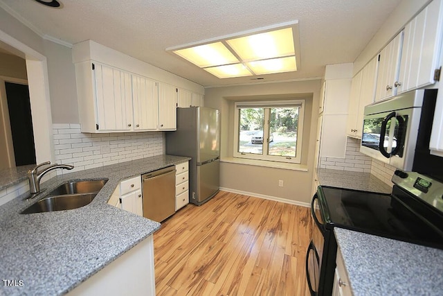 kitchen featuring white cabinets, sink, light hardwood / wood-style flooring, decorative backsplash, and appliances with stainless steel finishes