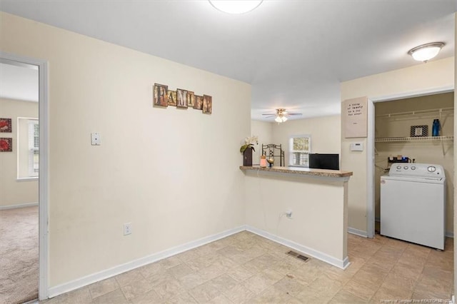 kitchen featuring kitchen peninsula, light carpet, washer / clothes dryer, and ceiling fan