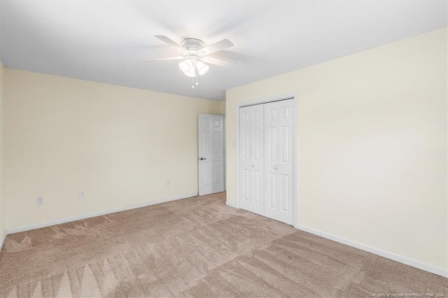 unfurnished bedroom featuring ceiling fan, a closet, and light colored carpet