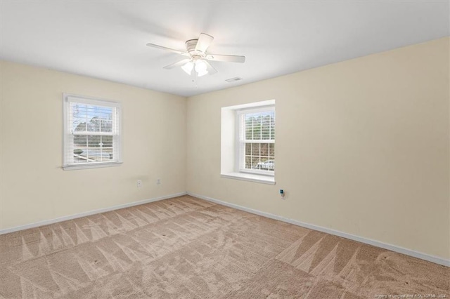 carpeted spare room with a wealth of natural light and ceiling fan