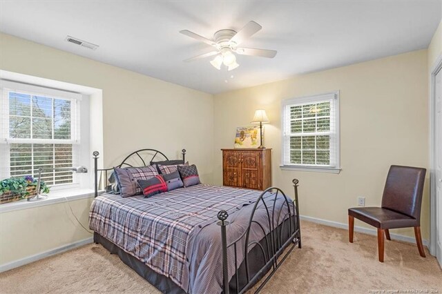 carpeted bedroom with multiple windows and ceiling fan