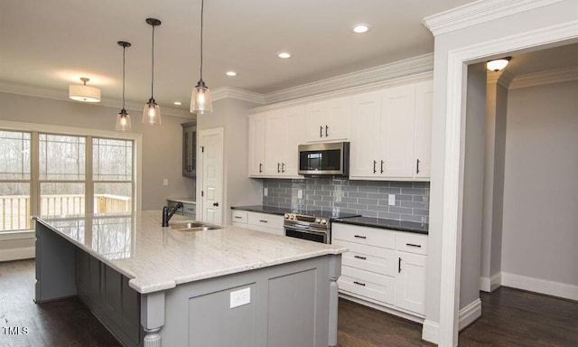 kitchen with white cabinetry, a center island with sink, sink, and appliances with stainless steel finishes